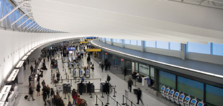 The ticketing hall at JetBlue’s new terminal at JFK is designed to accommodate increasing numbers of passengers arriving with boarding passes in hand, or using e-ticket kiosks. Traditional ticket counters are located at either end of the space, with several bag drop and e-ticket kiosks more centrally located.  (Credit: Nic Lehoux)